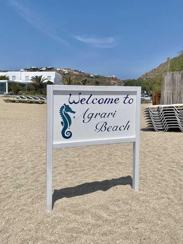 The sandy cove of Agrari Beach with its beach sign, Mykonos