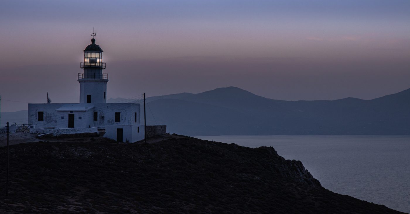 Armenistis lighthouse standing on the rocky headland of northwest Mykonos