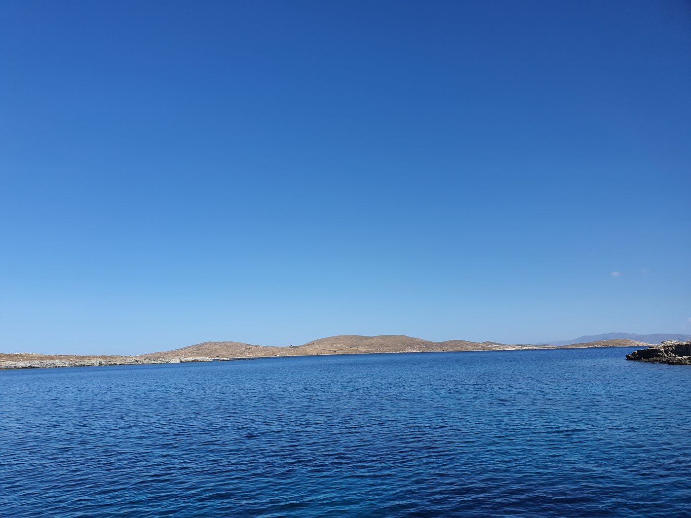 The low hills of Rhenia island seen across the water from an approaching boat