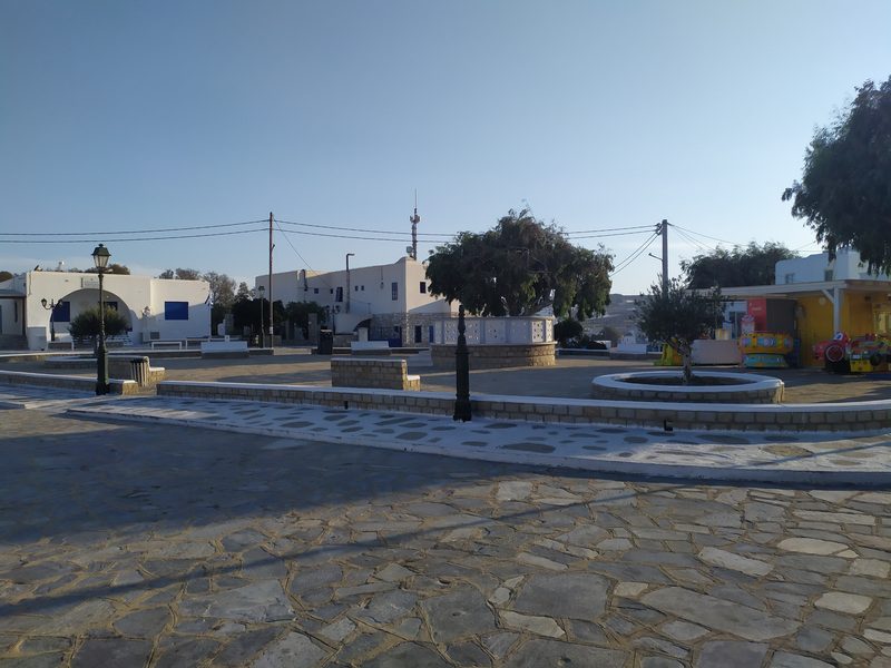 A charming street in Ano Mera Village, Mykonos, with traditional buildings and a whitewashed church.