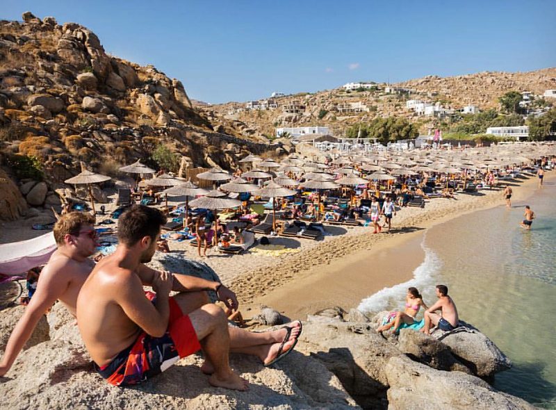 A serene view of Super Paradise Beach with clear blue waters and sandy shoreline in Mykonos, Greece.