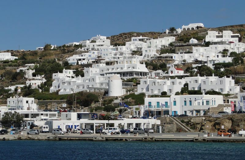 A picturesque street scene in Chora, Mykonos City, Greece, showcasing whitewashed buildings and vibrant bougainvillea.