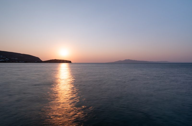 Sunrise over the Aegean Sea with the island of Mykonos in the distance from Agios Sostis, Tinos.