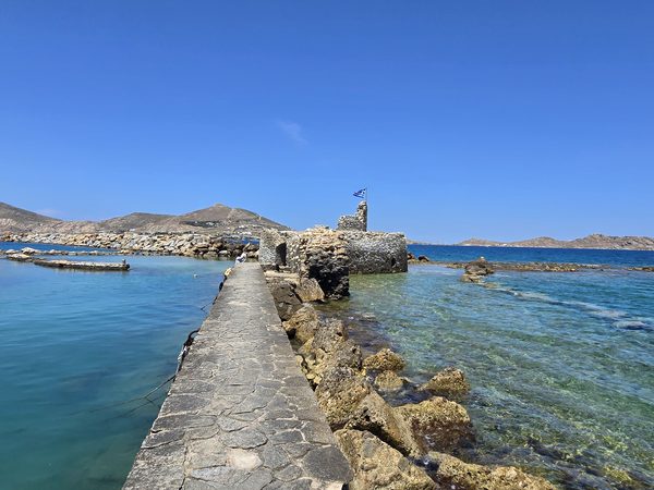 A stone breakwater leads out to the ruined Venetian fort in the water at Naoussa harbour, Paros