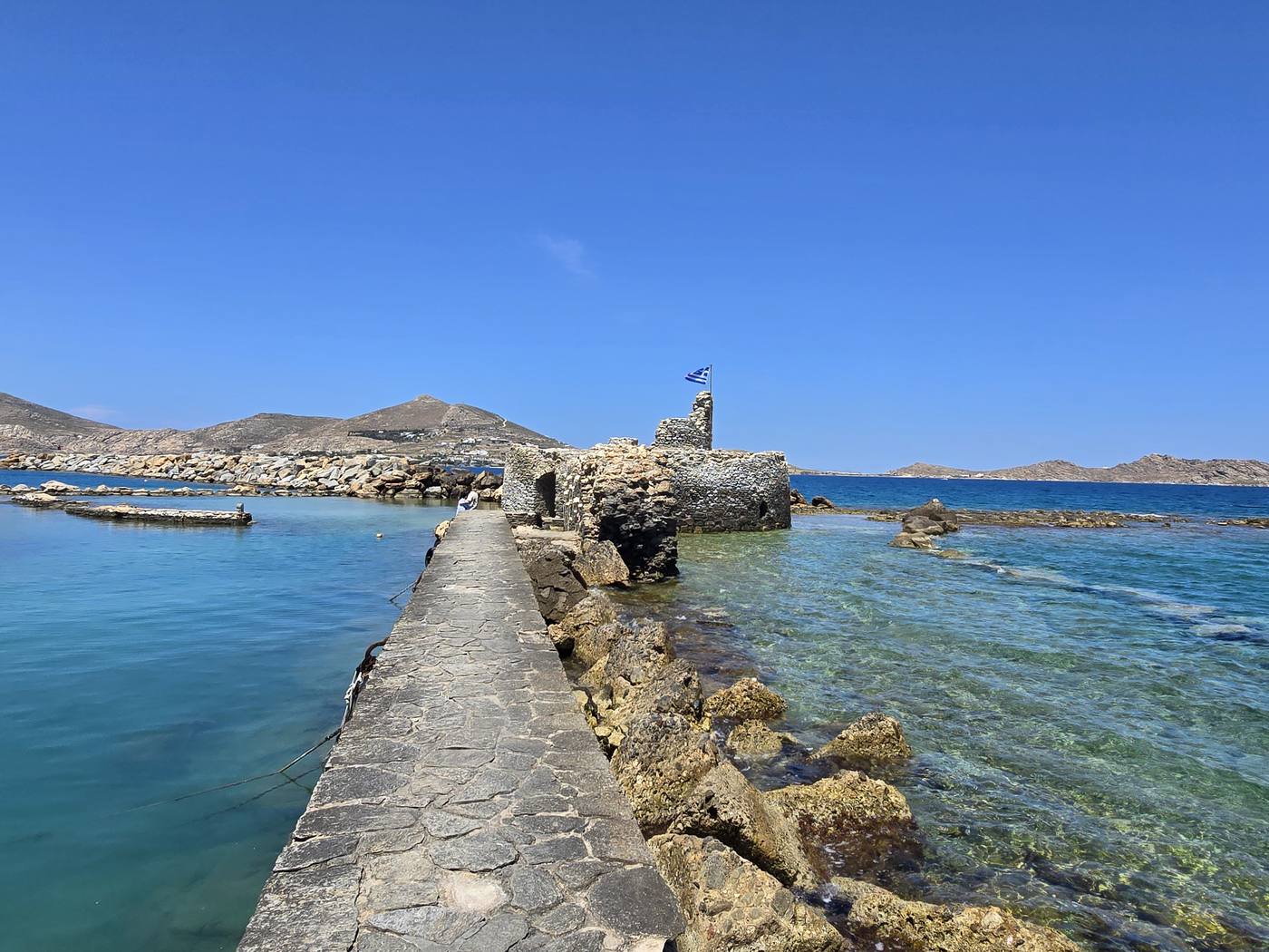 A stone breakwater leads out to the ruined Venetian fort in the water at Naoussa harbour, Paros