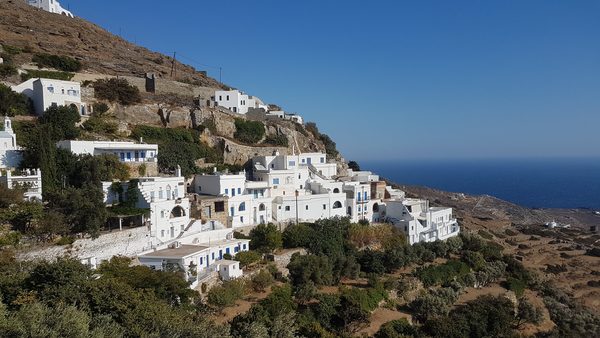 A whitewashed hillside village on Tinos with terraces of houses running down to the sea